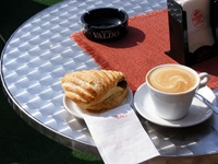 Eine Tasse Kaffee und ein süßes Gebäck aus Blätterteig auf einem Tisch