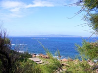 Wunderschöner Blick auf das tiefblaue Meer vor der Südküste Sardiniens und eine kleine Insel mit Leuchtturm.