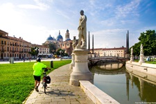 Ein Radfahrer schiebt sein Rad am Prato della Valle in Padua entlang.