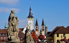 Steinfiguren auf der Alten Mainbrücke in Würzburg. Im Hintergrund sind die Doppeltürme des Doms zu erkennen.