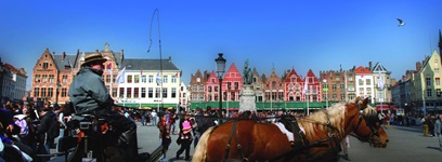 Buntes Treiben im Stadtzentrum von Brügge; im Bildvordergrund wartet eine Kutsche auf Gäste.