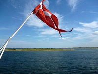 Die dänische Flagge weht am Heck eines Schiffes im Fahrtwind.