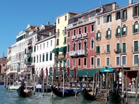 Bunte Häuserfassaden und im Wasser schaukelnde Gondeln am Canale Grande in Venedig.
