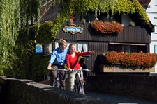 Zwei Radfahrer fahren stehen auf einer Brücke in Ulm, die Frau zeigt mit ihrer Hand auf etwas