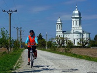 Ein Fahrradfahrer fährt auf einem Schotterweg am kleinen Kloster Saon im Donaudelta in Rumänien vorbei