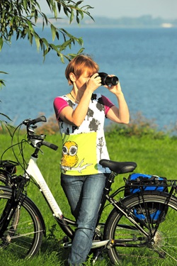 Eine Frau steht am Fahrrad und macht ein Foto der Landschaft der Mecklenburgische Seenplatte