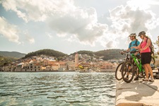 Zwei Mountainbikerinnen warten im Hafen von Pucisca auf ihr Schiff und genießen währenddessend den Ausblick auf die Stadt.