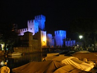Das Castello Scaligero in Sirmione wird abends in verschiedenen Farben angestrahlt.