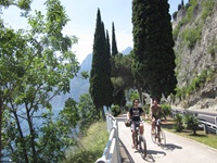 Zwei Radfahrer fahren auf einem asphaltierten Weg einen Berg am Gardasee hinauf