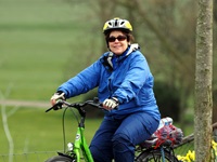 Eine Radlerin auf einem neongrünen Fahrrad schaut fröhlich in die Kamera.