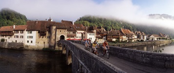 Vier Radfahrer auf der Jura-Route überqueren eine Brücke.