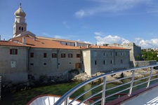 Blick auf den Kirchturm und die Rückseite von Häusern der Stadt Krk in der Kvarner Bucht von Kroatien vom Schiff aus gesehen