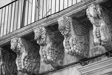 Kunstvoll gestaltete steinerne Tierfiguren stützen den Balkon eines Hauses im Salento.