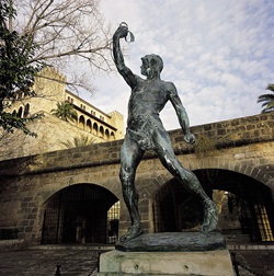 Blick auf eine Männerskulptur auf Mallorca, die in der rechten Hand etwas hält und hochstreckt.
