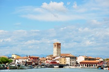 Boote auf dem Meer vor der Altstadt von Marano Lagunare mit ihrem Wahrzeichen "Torre Millenaria".