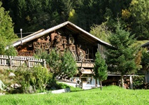 Blick auf ein typisches Bauernhaus mit viel Holzgeräten an der Hauswand im Mölltal