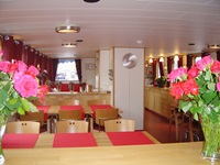 Gemütliche Holztische und -stühle mit Blumenschmuck erwarten die Gäste im Restaurant der MS Fleur.