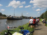 Reiseteilnehmer warten nach dem Ende der täglichen Radtour am Ufer auf die MS Gandalf.