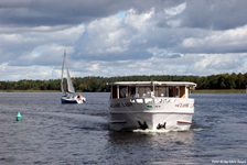 Die MS Classic Lady in Fahrt auf einem See der Masurischen Seenplatte - dahinter ist ein Segelboot
