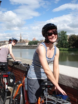 Zwei Radlerinnen machen am Arno eine kurze Pause, im Hintergrund die Silhouette von Florenz mit der Kuppel des Doms "Santa Maria del Fiore".
