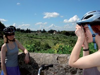 Eine Radlerin posiert vor einer typisch toskanischen Landschaft für ein Foto.
