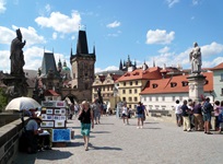 Touristen flanieren auf der für ihre Statuen berühmten Karlsbrücke in Prag, im Hintergrund die Prager Altstadt.