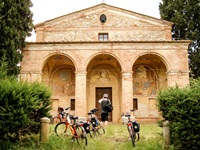Eine Radlergruppe in der Toskana nutzt eine Pause, um eine alte Kirche zu fotografieren.