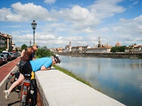 Zwei Radler machen am Ufer des Arno Pause und schauen auf die Skyline von Florenz.
