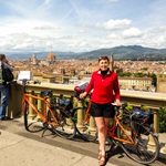 Eine Radlerin posiert vor der Skyline von Florenz für ein Foto.
