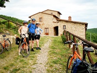 Drei Radler - zwei Frauen und ein Mann - lassen sich vor einem Landhaus im Chianti-Gebiet fotografieren.
