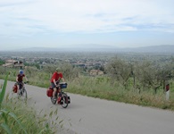 Zwei Radler fahren auf der Via degli Ulivi durch die umbrische Landschaft.