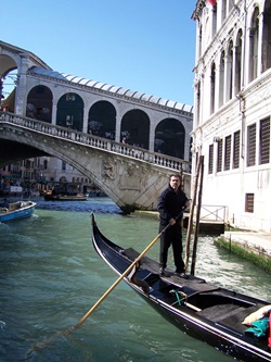 Ein stolzer Gondoliere stakt seine Gondel auf die weltberühmte Rialto-Brücke zu.