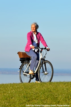 Eine Radlerin bei Prien, im Hintergrund der Chiemsee.