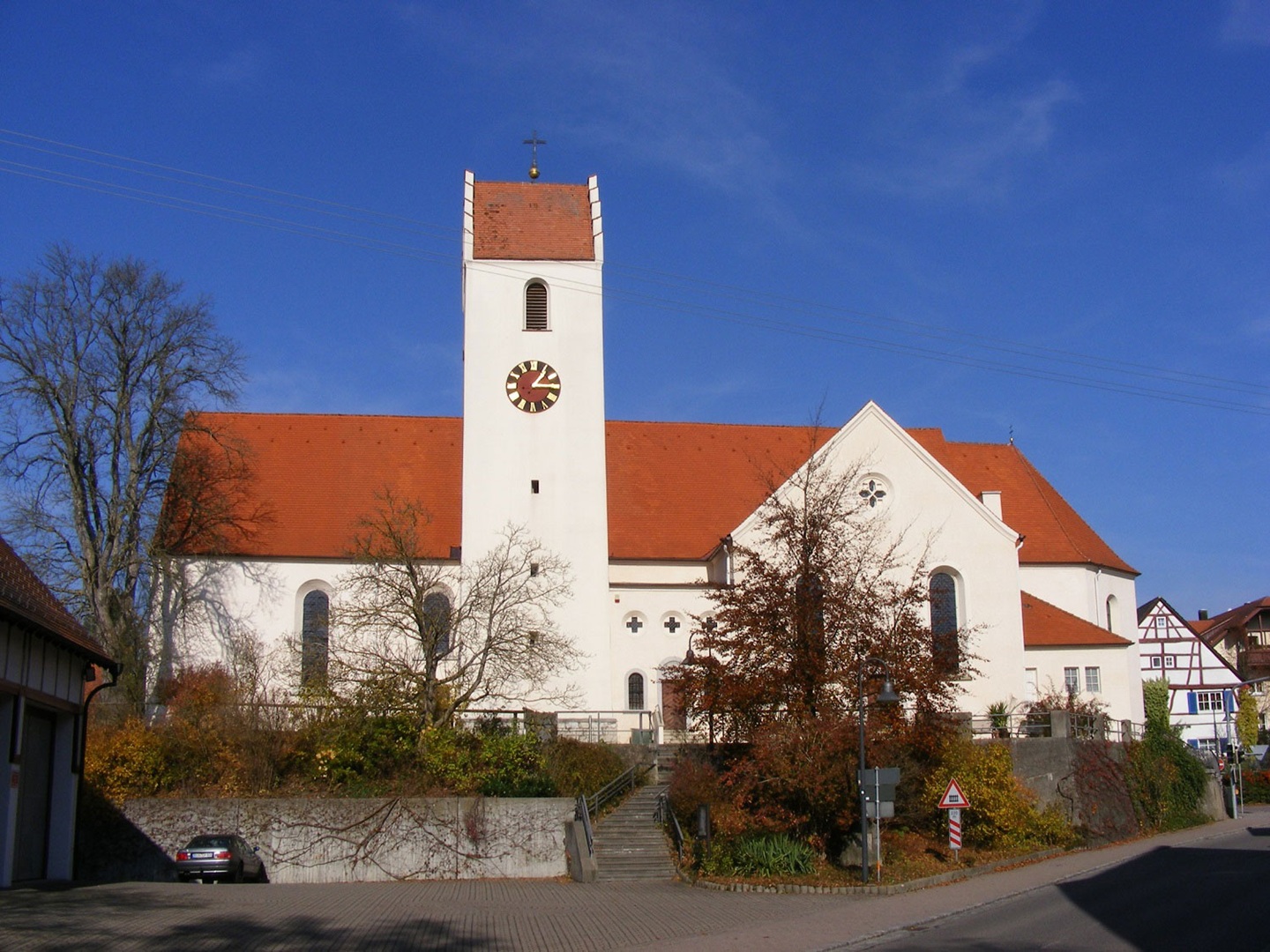 Die Pfarrkirch St. Peter und Paul in Sigmaringendorf mit weißer Kirchenfassade, rotem Dach und markantem Turm unter blauem Himmel