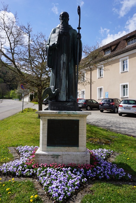 Denkmal vor der Erzabtei St. Martin zu Beuron, das den Heiligen Benedikt von Nursia mit Zepter und Buch in den Händen darstellt.