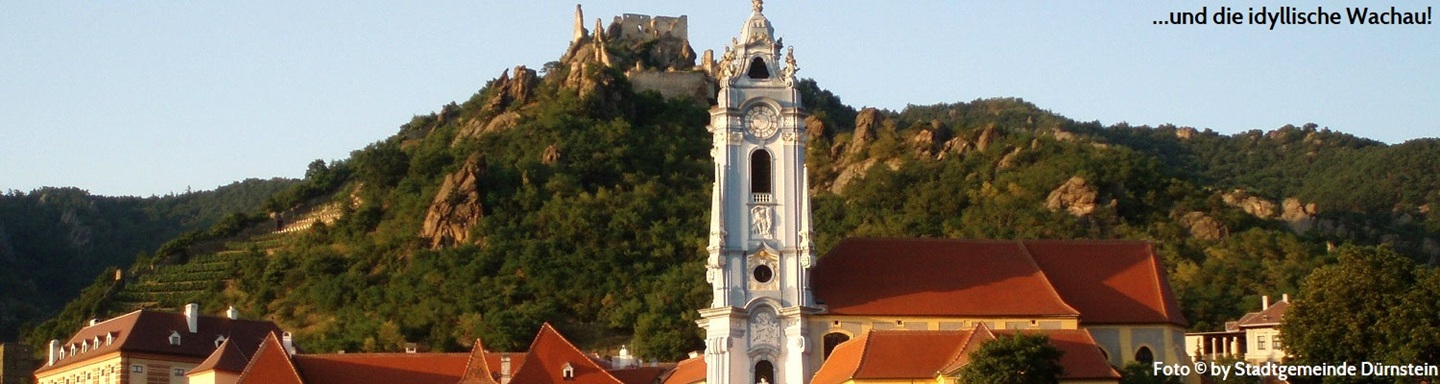 Blick auf den Kirchturm des Stifts Dürnstein, dahinter auf einem Berg die Ruine Dünstein, Österreich
