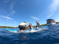 Eine Familie in einem Schlauchboot hat sichtlich Spaß auf dem Meer. Am rechten Bildrand ist die San Snova zu erkennen.