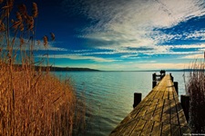 Ein hölzerner Steg und kristallklares Wasser an einem See in Bayern.