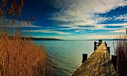 Ein hölzerner Steg und kristallklares Wasser an einem See in Bayern.