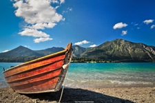 Ein hölzernes Ruderboot vor einer traumhaften Voralpenkulisse an einem See in Bayern.