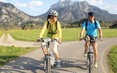 Ein junges Paar ist auf einem Radweg bei Füssen unterwegs.