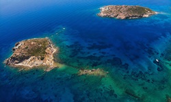 Die tiefblaue, teilweise türkis schimmernde Adria mit zwei kleinen Felsinselchen vor der Küste von Leros.
