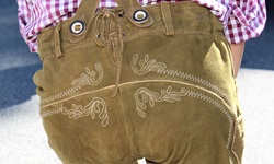 Ein fescher bayerischer Bursch präsentiert sein Hinterteil, das in einer traditionellen Lederhose steckt.