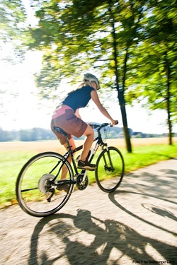 Eine Radlerin macht auf einem asphaltierten Radweg im Salzburger Land ordentlich Strecke.