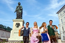 In Tracht gekleidete Touristen vor dem Mozart-Denkmal in Salzburg.