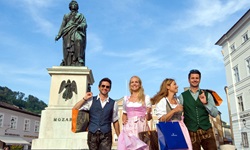 In Tracht gekleidete Touristen vor dem Mozart-Denkmal in Salzburg.
