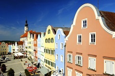 Die bunten Häuserfassaden rund um den Oberen Stadtplatz von Schärding, im Hintergrund die Stadtpfarrkirche St. Georg.