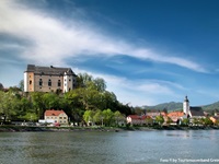 Schloss Greinburg thront über dem Donauufer; am rechten Bildrand ist die Pfarrkirche von Grein zu sehen.