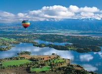 Ein bunt gestreifter Heißluftballon schwebt über dem Staffelsee.