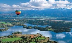 Ein bunt gestreifter Heißluftballon schwebt über dem Staffelsee.
